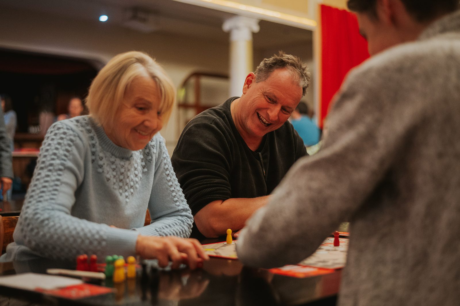 Zwei Spielerinnen und Spieler unterschiedlichen Alters lachen bei der Stadtmeisterschaft über dem Spielbrett